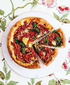 a pizza sitting on top of a white plate covered in sauce and veggies