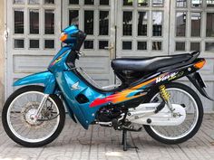 a blue motorcycle parked in front of a garage