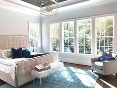 a bed room with a neatly made bed next to two chairs and a large window