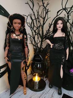 two dolls dressed in black are standing next to each other on a table with halloween decorations