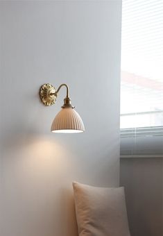 a wall light that is on the side of a white wall next to a pillow