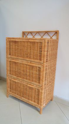 a wicker dresser with three drawers on the bottom and one drawer below it, in front of a white wall