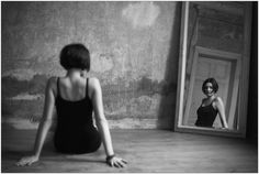 a woman sitting on the floor in front of a mirror