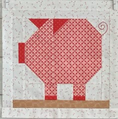 an elephant quilted on the side of a wall hanging from a wooden frame with red and white fabric