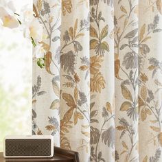 a window with curtains and a radio on it next to a flower vase filled with flowers