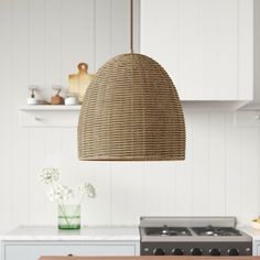 a wicker light hanging over a stove top oven in a kitchen with white cabinets