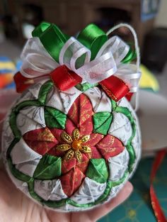 a hand holding an ornament decorated with ribbons