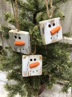 three snowmen made out of wooden blocks hanging from a tree