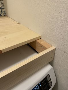 a clock sitting on top of a wooden shelf next to a dryer and wall