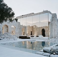 an old building with a mirrored pool in the middle and stone walls around it's perimeter