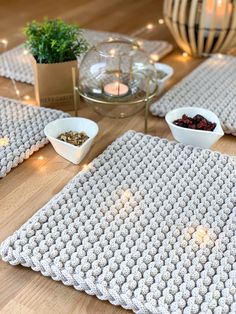 crocheted placemats and bowls on a wooden table with candles in the background