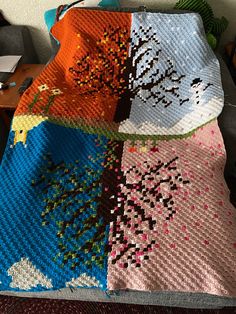 four different colored crocheted blankets on a table