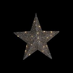 a silver star hanging from the ceiling with lights on it's side, against a black background