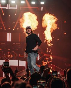 a man standing on top of a stage with fire in the air behind his back