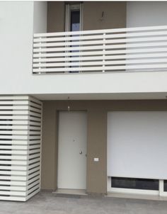 an apartment building with two garages and white balconies