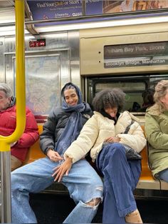 three people sitting on a subway car with their arms around each other