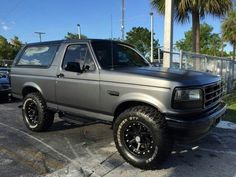 a silver truck parked in a parking lot next to other cars and palm tree's