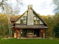 a large house in the middle of a grassy area with trees and bushes around it