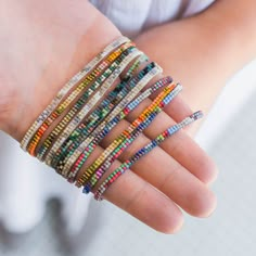 a person's hand holding several bracelets in different colors and sizes on their fingers