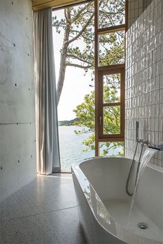 a large white bath tub sitting in a bathroom next to a window with an ocean view