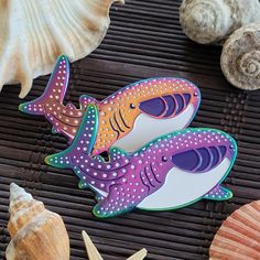 there are two stickers that look like sharks on the table next to shells and seashells