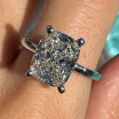 a close up of a person's hand with a diamond ring on their finger