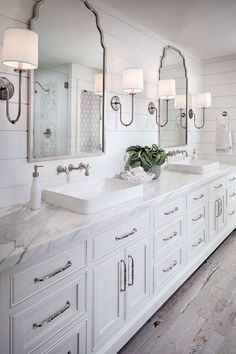 a white bathroom with double sinks and large mirrors on the wall next to each other