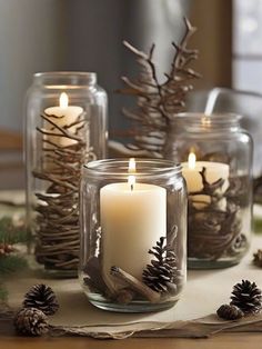 three glass jars filled with candles and pine cones