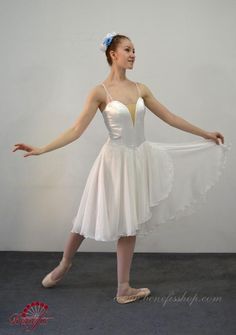 a woman in a white dress is standing with her arms spread out and she's wearing ballet shoes