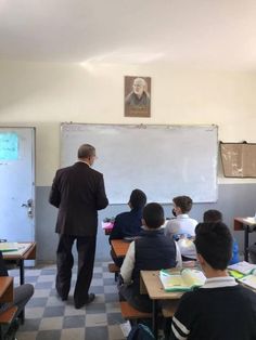 a man standing in front of a class room filled with children sitting at desks