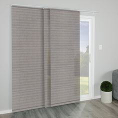 a living room with a gray couch and sliding glass doors that have blinds on them