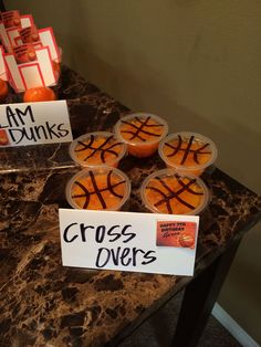 several plastic cups filled with oranges on top of a marble table next to signs that say cross overs