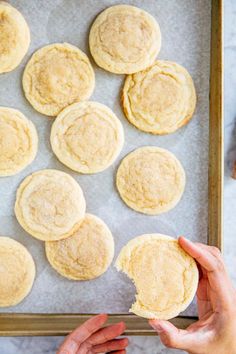 a person holding a cookie in front of some cookies on a baking sheet