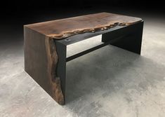 a bench made out of wood and metal in the middle of an empty room with concrete flooring