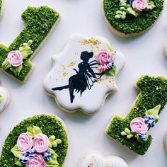 decorated cookies are arranged in the shape of letters and flowers on a white tablecloth