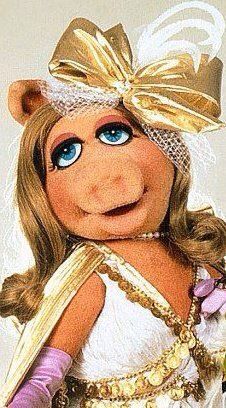 the miss piggy doll is dressed in white and gold with a big smile on her face