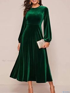 a woman wearing a green velvet dress with long sleeves and a high low neckline