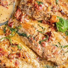 a pan filled with chicken covered in sauce and garnished with spinach leaves