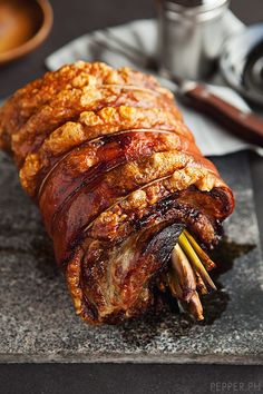 a large piece of meat sitting on top of a cutting board next to some chopsticks