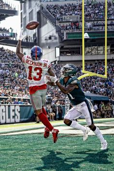 a football player jumping up into the air to catch a ball in front of another player