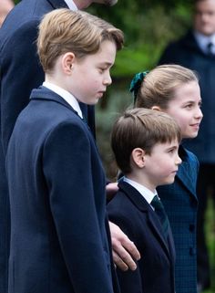 three young boys and one girl are standing in front of an older man wearing a suit