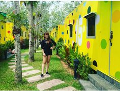 a woman standing in front of a yellow building with polka dot decorations on it's side