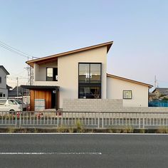 a white car parked in front of a house on the side of a road next to a fence