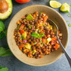 a bowl filled with beans and vegetables next to avocado