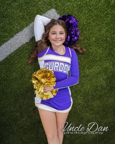 a cheerleader is laying on the grass with her pom poms in hand