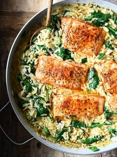 salmon and rice with spinach in a skillet on a wooden table, ready to be eaten