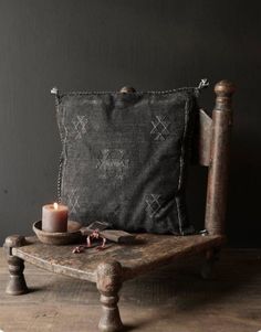 an old wooden chair with a candle on it next to a pillow and other items