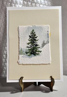 a painting of a pine tree is displayed on a white tablecloth with two antlers