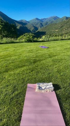 a yoga mat sitting on top of a lush green field next to a blue sky