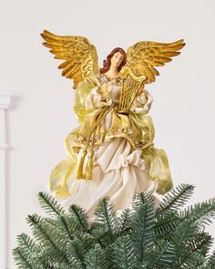 an angel figurine sitting on top of a christmas tree next to a potted plant